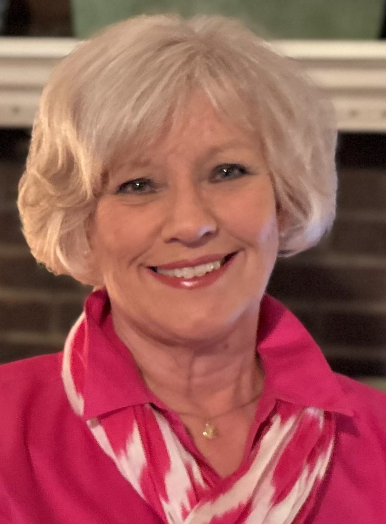 Photo of Kathy Conley wearing a pink outfit and pink-and-white scarf.