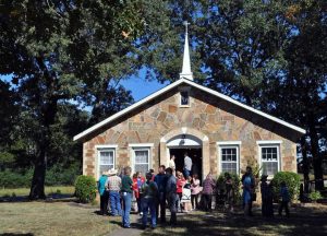 Small groups of people chatting on the lawn in front of a church