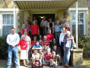 A group of people gathered, standing and sitting, on the front steps of the church
