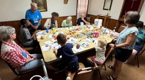 People sitting around a table holding craft supplies and pastires