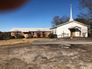 The outside of Newberry Chapel, a white clapboard buidling with a brick ell