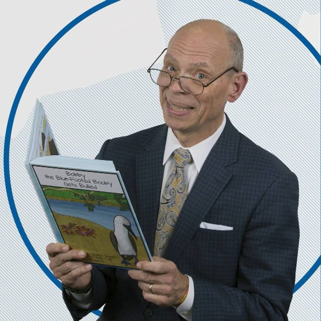 Photo of Craig O'Neill wearing glasses and reading a book.
