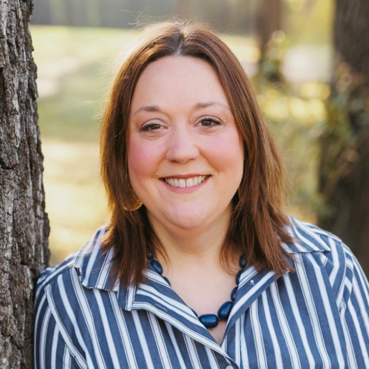 A smiling woman wearing a blue and white striped, collared shirt