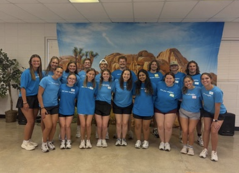 Group of smiling people wearing blue t-shirts and dark shorts